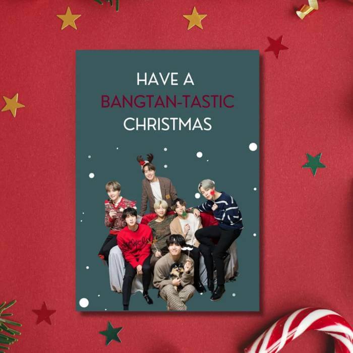 BTS Christmas postcard with "Have a Bangtan-tastic Christmas" message, featuring all members in festive attire, surrounded by holiday decor.