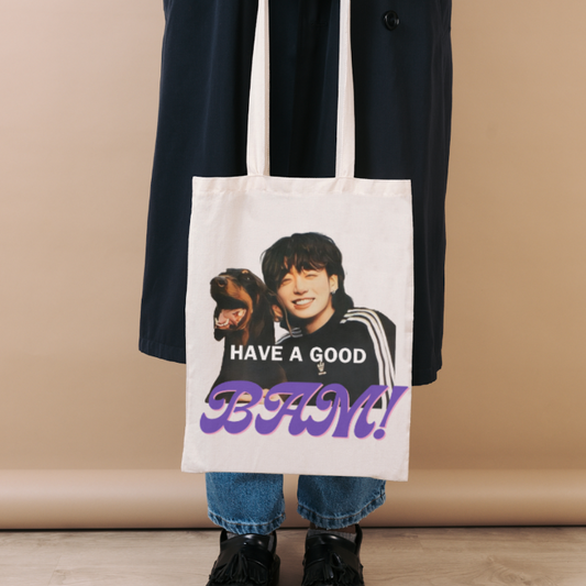 Woman holding a natural totebag with BAM JK design