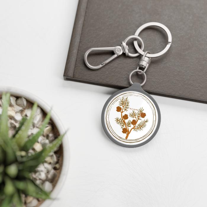 Silver keychain with suga's birthflower larch on a table