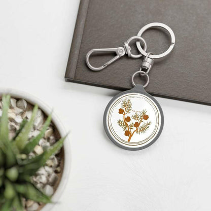 Silver keychain with suga's birthflower larch on a table