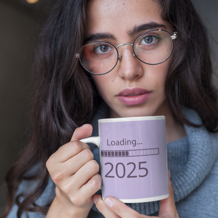 Woman with glasses holding a mug with design BTS return loading 2025