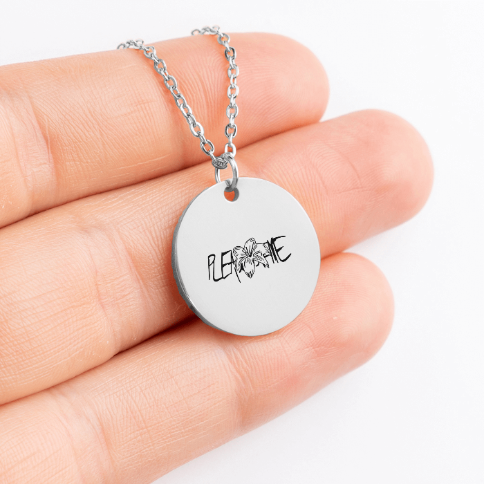 Hand holding JK Tigerlily birthflower silver coin necklace with "Please love me" engraved