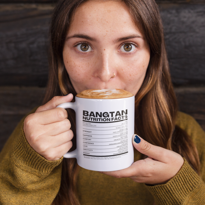 Woman with brown hair holding a coffee mug with bangtan nutrition facts design