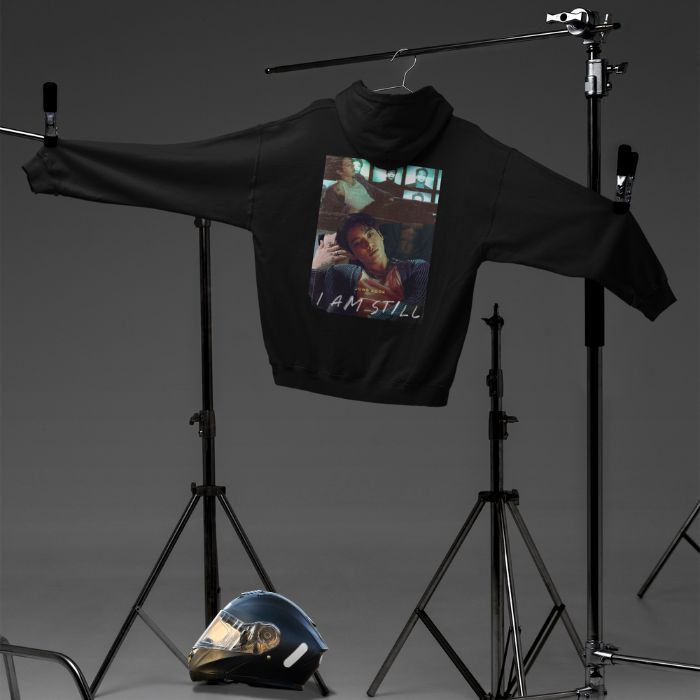 Pullover black hoodie back view with JK design hanging on a tripod and a motor helmet aside