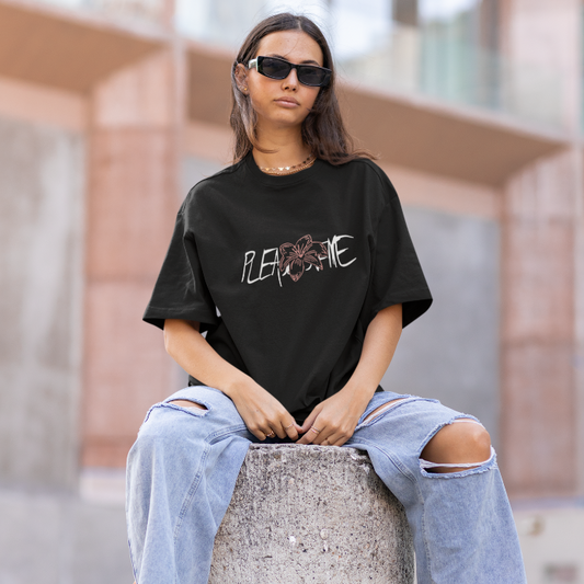 Young woman sitting on a concrete pillar wearing oversized tshirt with JK tatoo design