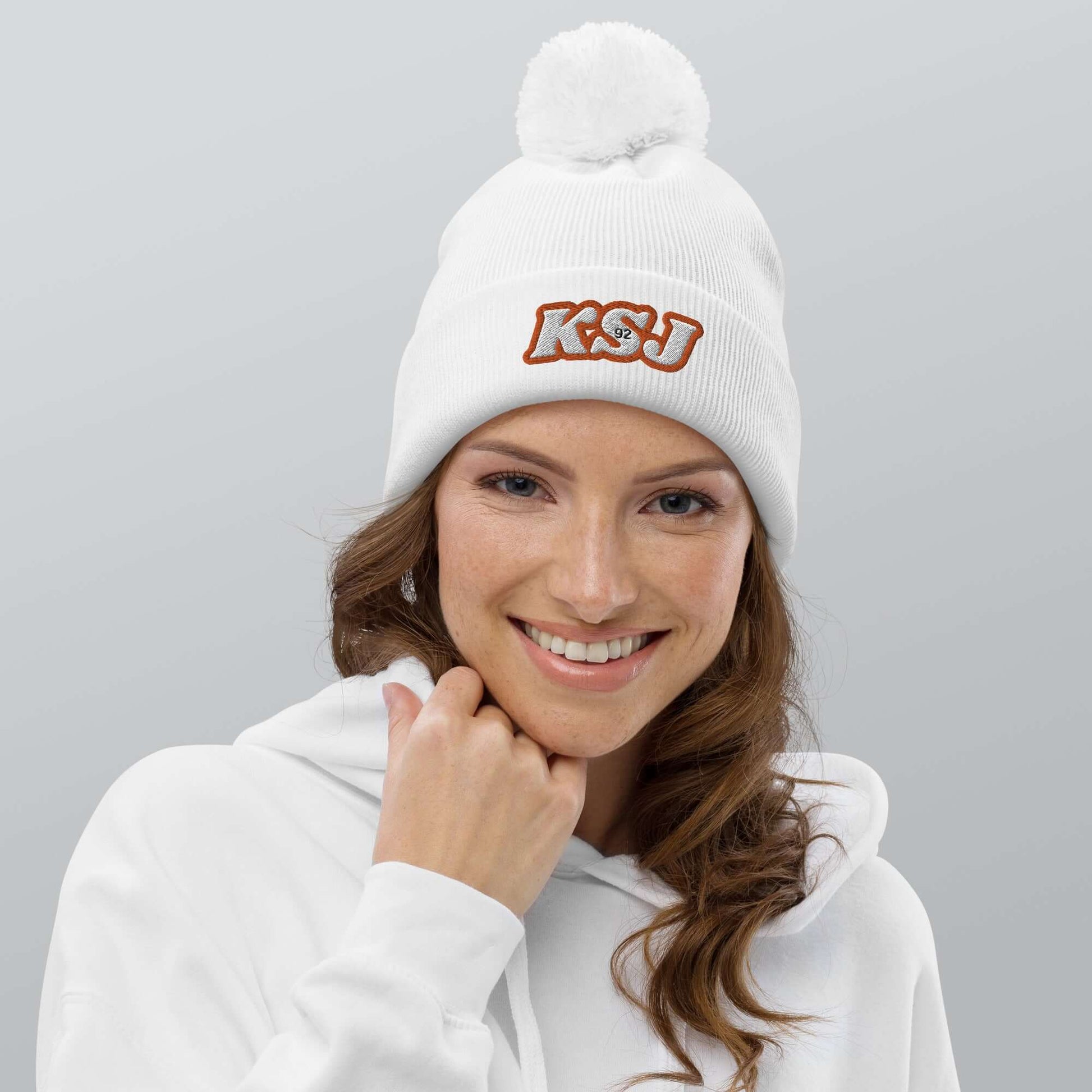 Woman smiling in Jin's warm and bright pom pom beanie, showcasing cozy, double-layer soft-touch acrylic, winter fashion accessory.